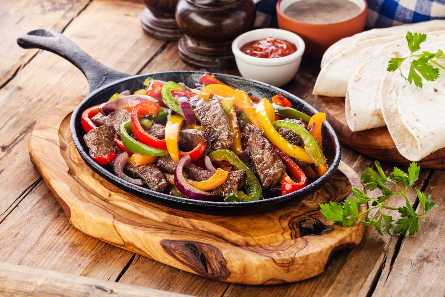 Beef Fajitas with colorful bell peppers in pan and tortilla brea